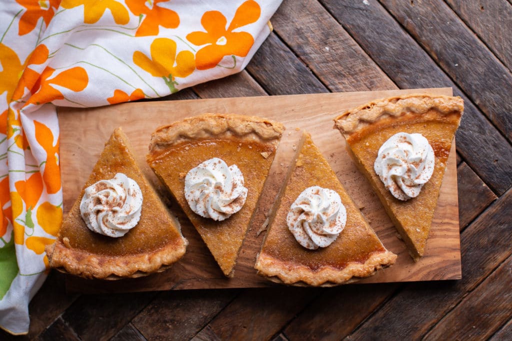 4 slices of pumpkin pie with napkin on the side.