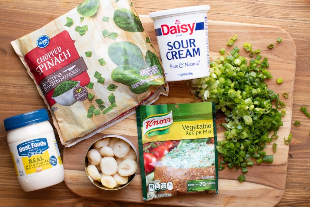 ingredients for cold spinach dip on wooden cutting board.