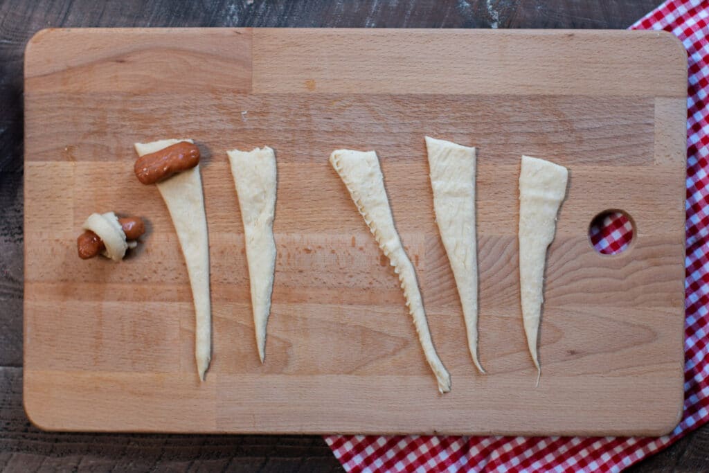 A wooden cutting board, with Dough and Sausage